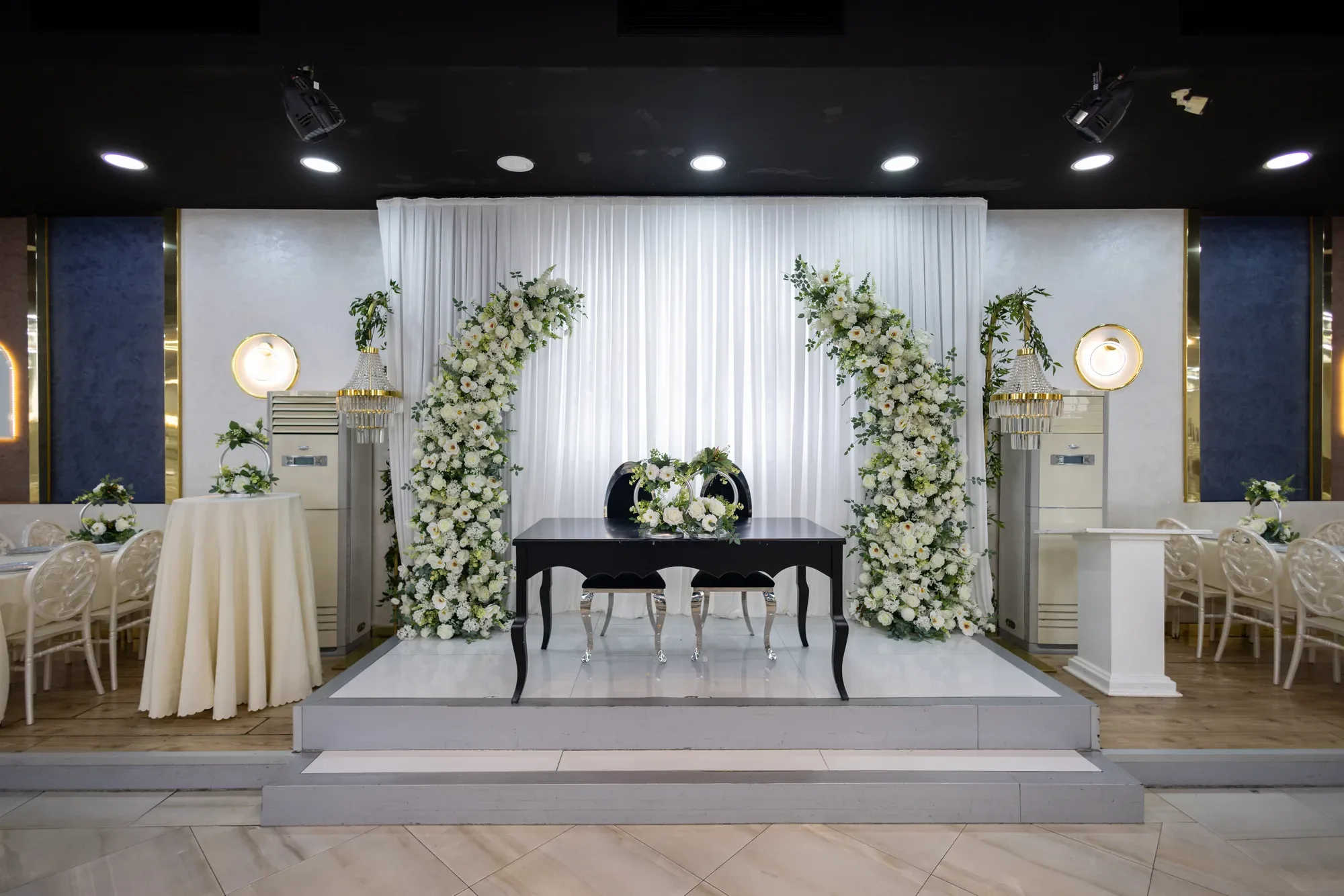 Klasik Salon: beyaz çiçek kemerleri arasında nişan masası
